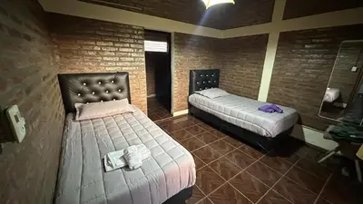 a bedroom with two beds and a brick wall at Loft estilo rustico Alta Cba Wifi 100Mb y Escritorio in Cordoba