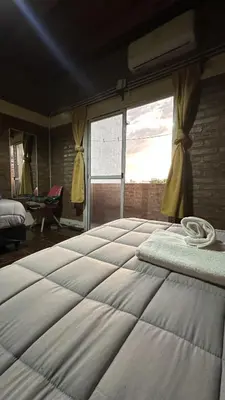 a large bed in a room with a large window at Loft estilo rustico Alta Cba Wifi 100Mb y Escritorio in Cordoba