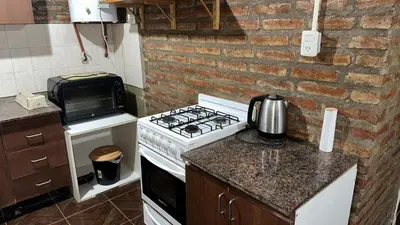 a kitchen with a stove and a brick wall at Loft estilo rustico Alta Cba Wifi 100Mb y Escritorio in Cordoba