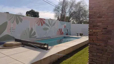 a swimming pool in front of a fence with a mural at Remanso in Alta Gracia