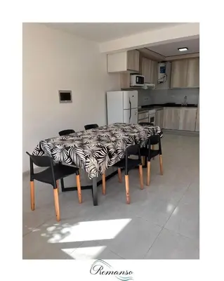 a dining room table with black chairs and a kitchen at Remanso in Alta Gracia