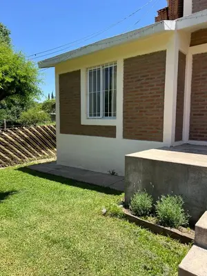 a house with a grass yard in front of it at Casa Temporal Bialet Massé in Bialet Massé