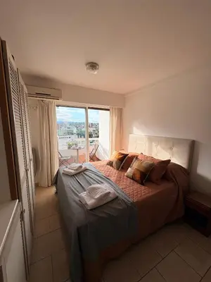 a bedroom with a large bed with a large window at El Balcón de Margy Villa Carlos Paz Centro Galeria Acuario Acogedor monoambiente con vista al rio in Villa Carlos Paz