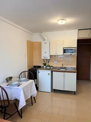 a kitchen with white cabinets and a table with a table cloth at El Balcón de Margy Villa Carlos Paz Centro Galeria Acuario Acogedor monoambiente con vista al rio in Villa Carlos Paz