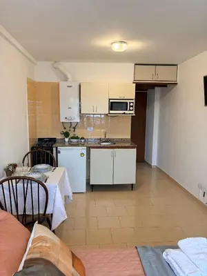 a kitchen with white cabinets and a table and a kitchen with a table at El Balcón de Margy Villa Carlos Paz Centro Galeria Acuario Acogedor monoambiente con vista al rio in Villa Carlos Paz