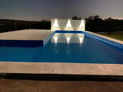 an empty swimming pool at night with lights on it at Lucero de Brochero in Villa Cura Brochero