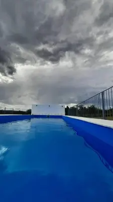 a large blue swimming pool under a cloudy sky at Lucero de Brochero in Villa Cura Brochero