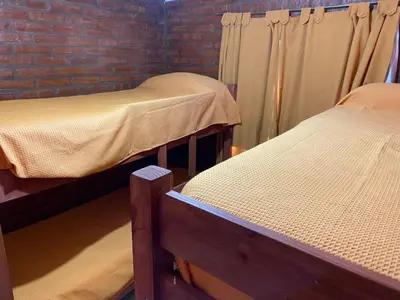 three beds in a room with a brick wall at Lucero de Brochero in Villa Cura Brochero