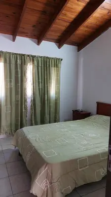 a bedroom with a large bed with green curtains at Duplex al pie de las sierras in Villa Carlos Paz