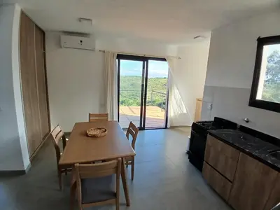 a dining room with a table and a kitchen with a view at Balcon del rio in Cavalango