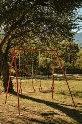 an empty swing set in a park with a tree at Cabañas Achikilla in Las Calles