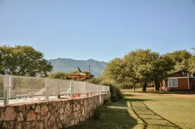 a stone retaining wall with a fence and a house at Cabañas Achikilla in Las Calles