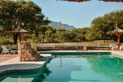 a swimming pool with chairs and a table and a umbrella at Cabañas Achikilla in Las Calles