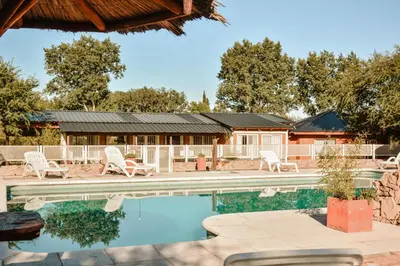 a swimming pool with chairs and a house at Cabañas Achikilla in Las Calles
