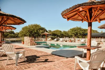 a pool with chairs and a table and umbrellas at Cabañas Achikilla in Las Calles