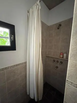 a shower with a white curtain in a bathroom at Casa de diseño en Costa Azul in Villa Carlos Paz