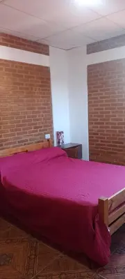 a large bed in a room with a brick wall at Bella Fefi in Villa Cura Brochero