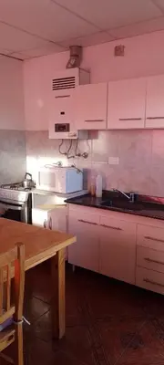 a kitchen with white cabinets and a wooden table at Bella Fefi in Villa Cura Brochero