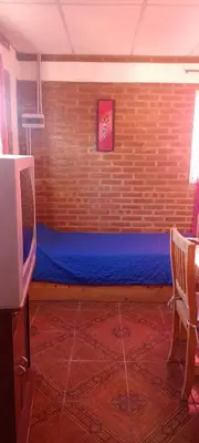 a room with a blue bed in a brick wall at Bella Fefi in Villa Cura Brochero