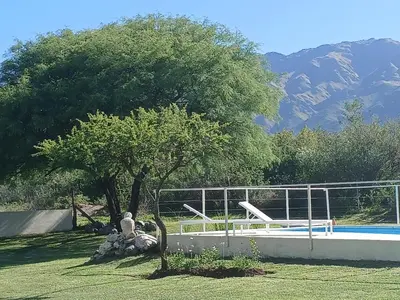 a man sitting under a tree next to a pool at Complejo El Caldén in Merlo