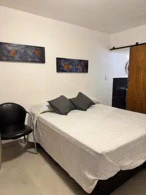 a bedroom with a bed and a black chair at Moderno dpto zona norte 1 dorm in Cordoba