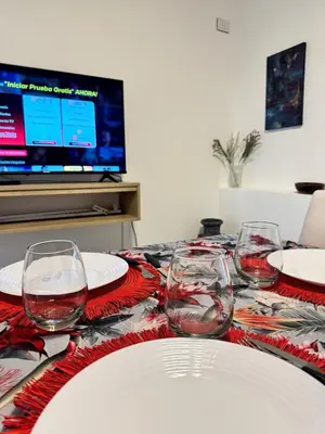 a table with plates and wine glasses and a television at Moderno dpto zona norte 1 dorm in Cordoba
