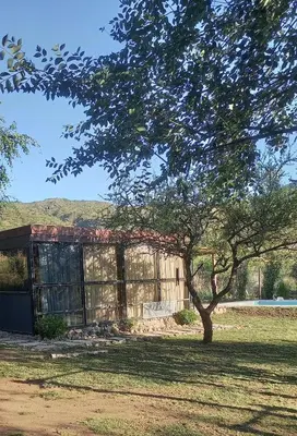a building in a field with a tree in the foreground at Lo de Nor - Refugio de Montaña in San Antonio de Arredondo