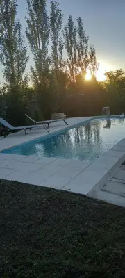 a swimming pool with the sun setting in the background at Lo de Nor - Refugio de Montaña in San Antonio de Arredondo