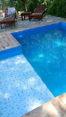 a blue swimming pool with a bench in the background at Casa con piscina privada en las sierras de Córdoba in Villa Anizacate