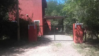 a gate in front of a red building at Casa con piscina privada en las sierras de Córdoba in Villa Anizacate