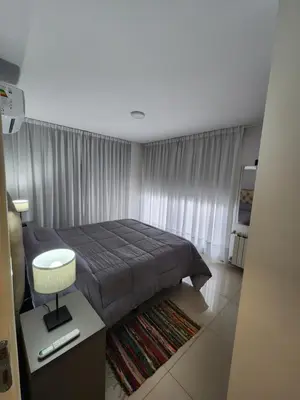 a bedroom with a bed and a table and a window at Civis Tower Excepcional Departamento in Villa Carlos Paz
