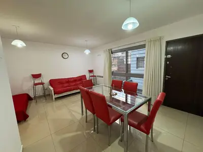 a living room with a glass table and red chairs at Myng Departamento en el centro de Carlos Paz in Villa Carlos Paz