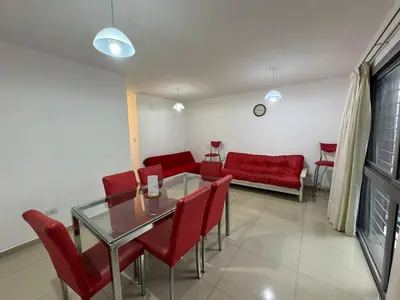 a living room with a glass table and red chairs at Myng Departamento en el centro de Carlos Paz in Villa Carlos Paz