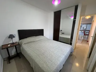 a bedroom with a bed and a table and a mirror at Myng Departamento en el centro de Carlos Paz in Villa Carlos Paz