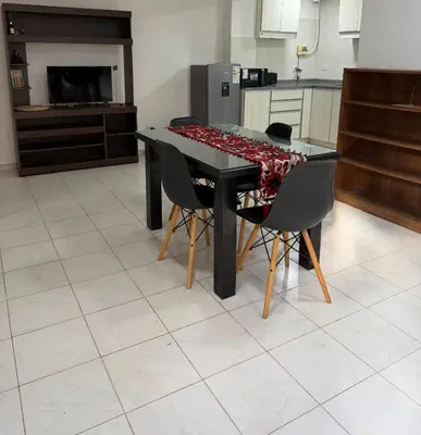 a kitchen with a black table with chairs and a kitchen with a stove at Departamento PA in Villa Carlos Paz