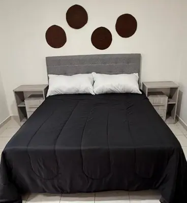 a bedroom with a black bed with two end tables at Departamento PA in Villa Carlos Paz