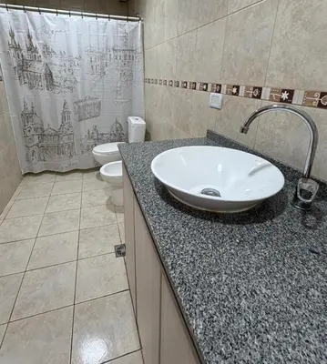 a bathroom with a sink and a toilet and a shower curtain at Departamento PA in Villa Carlos Paz