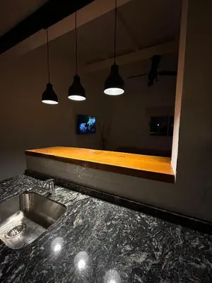 a kitchen with a counter with a sink and lights at Disfruta casa de bosque a metros de AV San martin y minutos del lago in Villa Carlos Paz