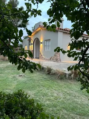 a white house with a gate in a yard at Disfruta casa de bosque a metros de AV San martin y minutos del lago in Villa Carlos Paz