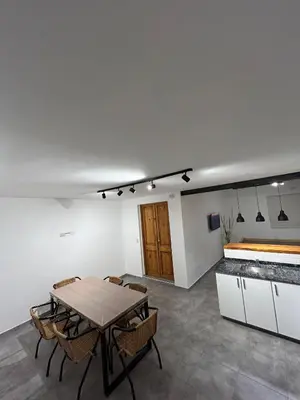 a dining room with a table and chairs and a counter at Disfruta casa de bosque a metros de AV San martin y minutos del lago in Villa Carlos Paz