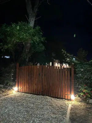 a wooden fence with lights on it at night at Disfruta casa de bosque a metros de AV San martin y minutos del lago in Villa Carlos Paz