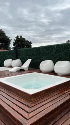 a hot tub on a wooden deck with white chairs at Astoria Hotel in Villa Carlos Paz
