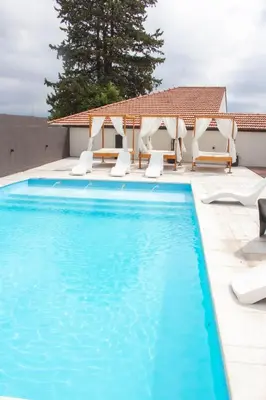 a swimming pool with lounge chairs and a house at Astoria Hotel in Villa Carlos Paz