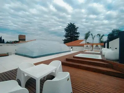 a deck with white chairs and a table on a building at Astoria Hotel in Villa Carlos Paz