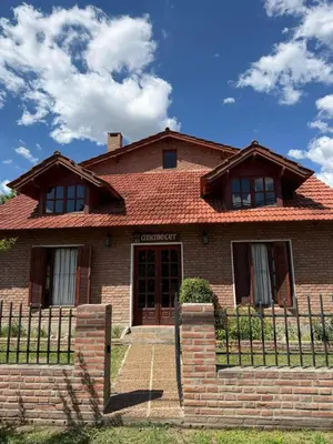 a brick house with a fence in front of it at El Amanecer in Mina Clavero