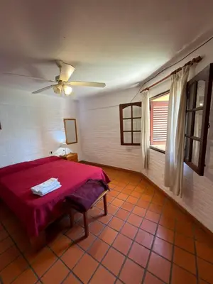 a bedroom with a red bed and a window at El Amanecer in Mina Clavero