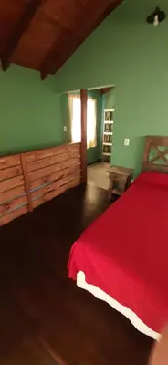 a bedroom with a red bed and green walls at TARDES De MONTAÑA in Santa Rosa de Calamuchita