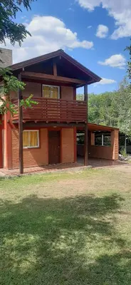 a large wooden house with a lawn in front of it at TARDES De MONTAÑA in Santa Rosa de Calamuchita