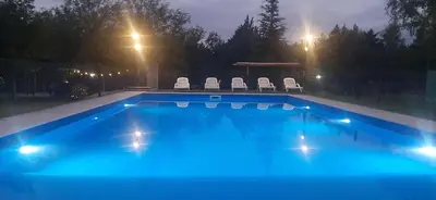 a swimming pool at night with chairs and a gazebo at TARDES De MONTAÑA in Santa Rosa de Calamuchita