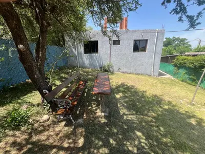 a bench sitting under a tree next to a house at Portal del rio mina clavero in Mina Clavero